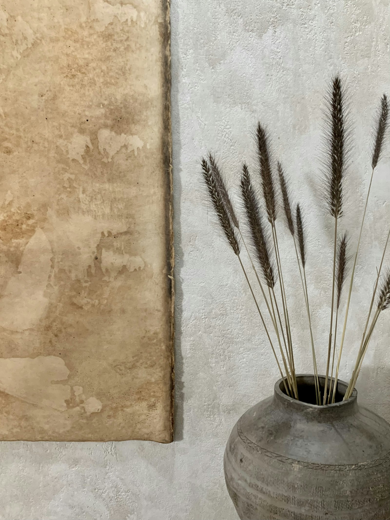 Neutral dried stems in a vase by a wall